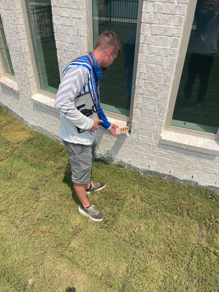 Home inspector examining brick veneer and window sills on the exterior of a Pearland TX home