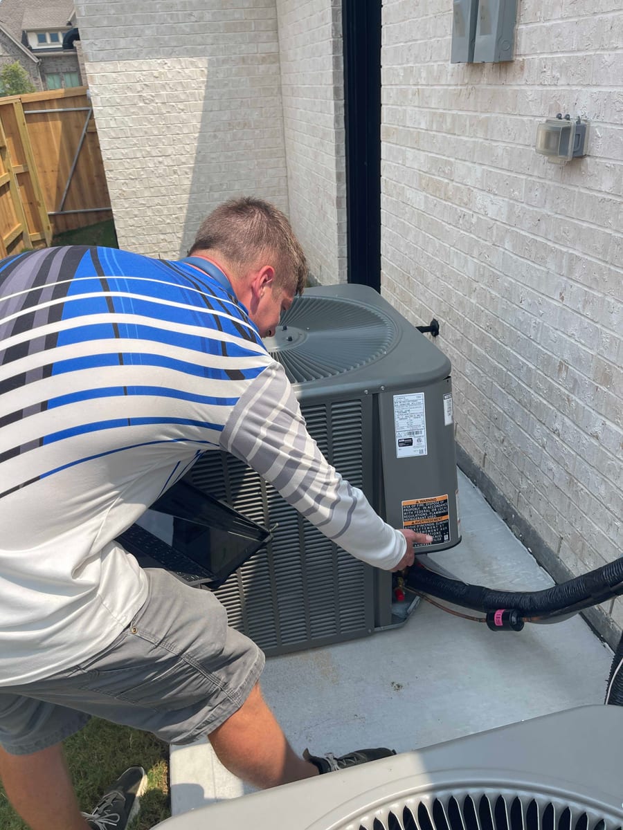 Home inspector examining an outdoor air conditioning condenser and refrigerant lines at a Pearland TX home