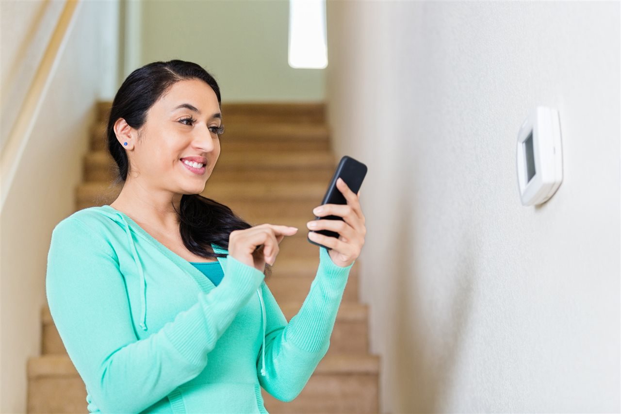 a woman smiling holding her phone | GC Home Inspection | Home Security Pearland