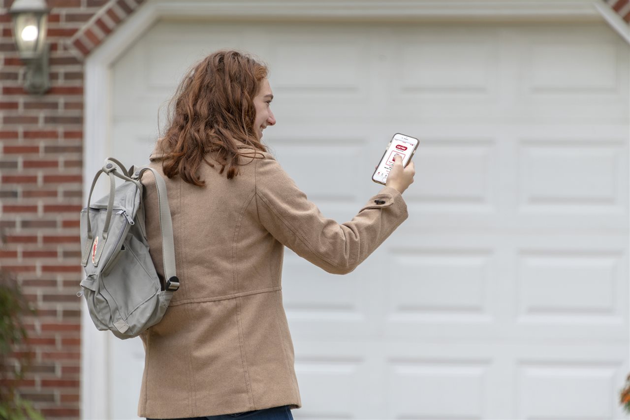 a woman looking at her phone outside the garage | GC Home Inspection | Connectivity Chicago
