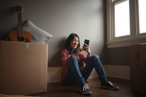 a girl sitting looking at her phone smiling | GC Home Inspection | Moving made Simple Pearland