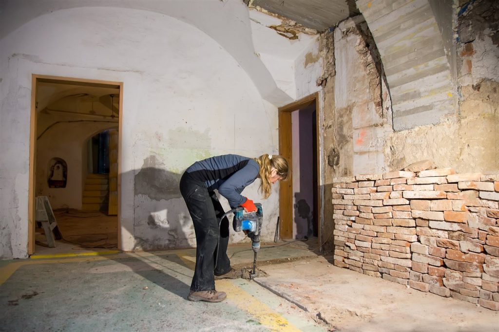 woman drilling the basement floor | GC Home Inspection | Bathroom in the basement Pearland